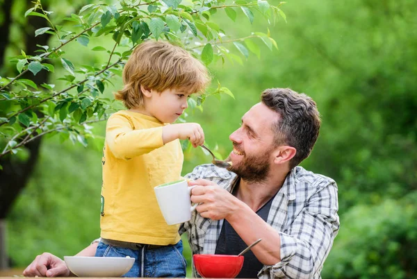 Food habits. Little boy with dad eating food nature background. Summer breakfast. Healthy food concept. Father son eat food and have fun. Feeding baby. Menu for children. Family enjoy homemade meal — Stock Photo, Image