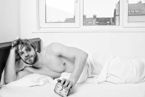 Good morning. Man unshaven lay bed hold alarm clock. Stick schedule same bedtime wake up time. Regulate your bodys clock. Enough sleep for him. Man unshaven tousled hair wakeful face having rest — Stock Photo, Image