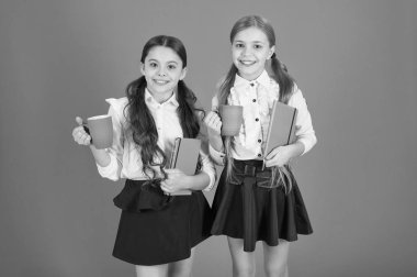 Kız çocuklar okul üniforması turuncu arka plan. Kız öğrenci kitap veya Not defteri ve kupa tutun. Okul rutin. Sakin ol molası. Çay molası sırasında içme. Okul arkadaşları ile içki rahatlatıcı. Öğrenci olmanın tadını çıkarın