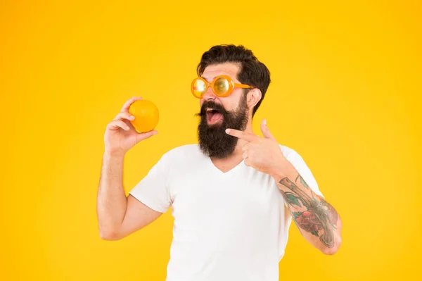 Juicy fruit. Summer nutrition. Hipster with beard in summer mood. Man bearded hipster in orange sunglasses on yellow background. Cheerful guy with ripe fruit. Summer vacation. Fresh and healthy — Stock Photo, Image
