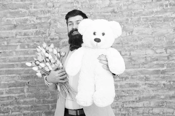 Bear toy. Enjoying spring holiday. Bearded man with tulip bouquet and bear. Spring gift. Bearded man with flowers. Cute bear. March 8. Love date. international holiday. Womens day. Big bear gift