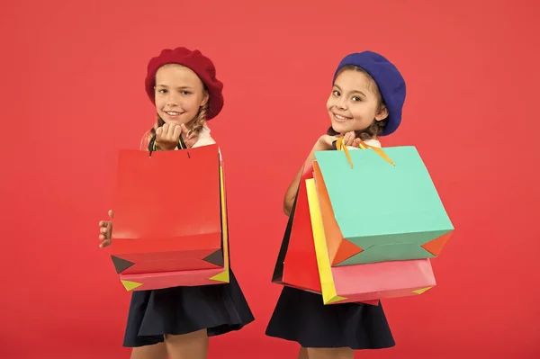 Señales de que eres adicto a las compras. Niños lindas colegialas sostienen manojo bolsas de compras. Niños alumnos satisfechos comprando fondo rojo. Obsesionado con centros comerciales y de ropa. Concepto Shopaholic —  Fotos de Stock