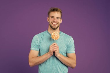 Adam büyük renkli tatlı lolipop yemek. Kıl adamla Lolipop sever. Yemek kavram hile. Şeker sağlık için zararlı. Adam lolipop şeker menekşe arka plan tutun. Çocukluk tadına. Lolipop eğlenceli