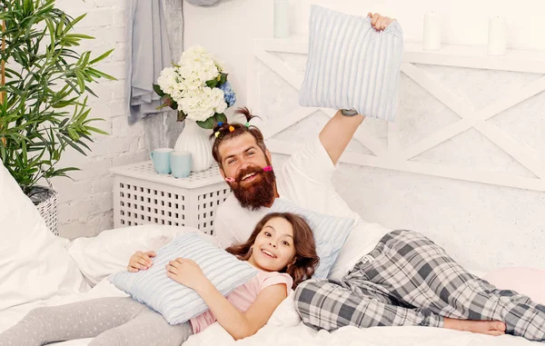 Man skäggiga hipster med barnslig frisyr färgglada ponytails och dotter i pyjamas. Kille och flicka koppla av i sovrummet. Pyjamas stil. Ha kul pyjamas fest. Pyjamasparty. Lycklig faderskap — Stockfoto