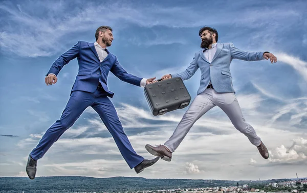 Businessmen jump fly mid air while hold briefcase. Case with raise your business. Successful transaction between businessmen. Briefcase handover in heaven blue sky background. Easy deal business