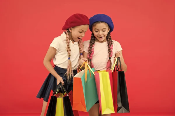 Kinder freuen sich über roten Hintergrund beim Einkaufen. Besuch eines Bekleidungsgeschäfts. Rabatt- und Verkaufskonzept. Kinder niedliche Mädchen halten Einkaufstüten. Shopping-Rabattsaison. Sonderangebot. Toller Tag zum Einkaufen — Stockfoto