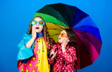 Bright umbrella. Happy childhood. It is easier to be happy together. Be rainbow in someones cloud. Rainy weather with proper garments. Walk under umbrella. Kids girls happy friends under umbrella clipart