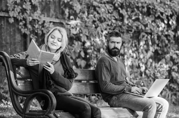 Libri contro computer. amante del libro nel parco. uomini e donne barbuti sulla panchina del parco. week end primaverile relax. primo incontro di coppia intelligente. la vita degli studenti. donna ha letto un libro. uomo utilizzare la tecnologia informatica — Foto Stock