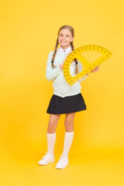 Derse hazır olmak. Sevimli kız öğrenci matematik dersi için protractor tutarak. Geometri dersine hazırlanan küçük çocuk. Okul dersinde ölçüm aleti kullanarak sevimli küçük kız