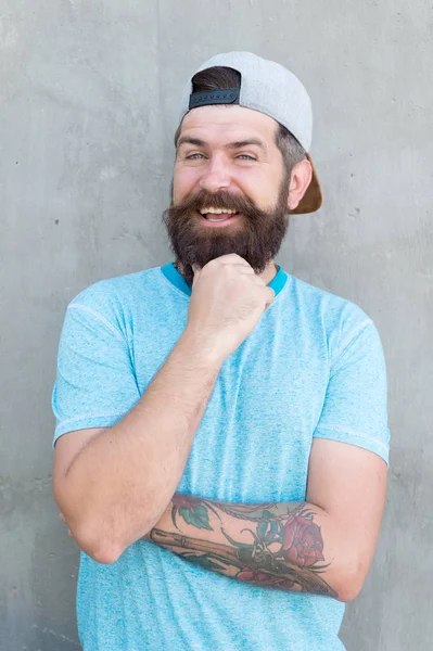 For a casual touch. Happy hipster in casual and comfy outfit on grey wall. Bearded man smiling in casual streetwear style. Styling casual weekend wear