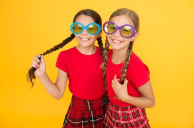 Çocuklar moda arkadaşlar sarı arka plan üzerinde güneş gözlüğü poz. Yaz moda trendi. Yaz eğlencesi. Yaz aksesuarı. Kızlar sevimli kız benzer kıyafetler yaz sezonu için renkli güneş gözlüğü giymek