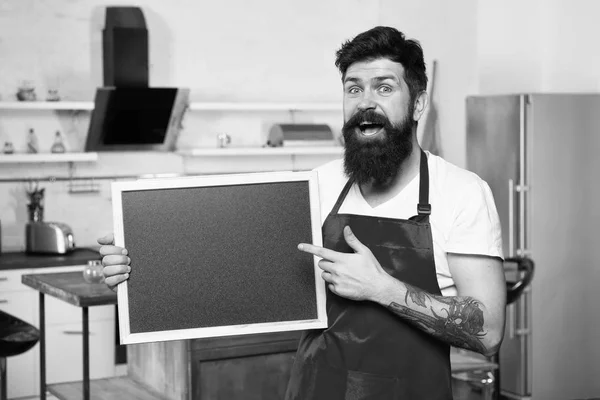 Apontando espaço de cópia. Homem maduro. Cozinheiro barbudo. Homem barbudo de avental vermelho. Restaurante ou menu de café. Anúncio. Chef homem com bordo, espaço de cópia. Hipster na cozinha. Menu restaurante — Fotografia de Stock