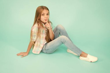 Sessizlik tutmak. Sevimli kız çocuk ağız üzerinde parmak tutmak. Uzun sarı saçlı küçük kız. Rahat tarzı giyen küçük çocuk. Küçük moda model güzellik bakışla. Ayak uydurarak moda kız