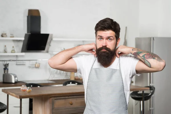 Preparar la cocina tradicional. Cocinero serio antes de preparar deliciosa cocina en la cocina. Chef barbudo con delantal en el restaurante con cocina gourmet. Aquí se sirve cocina local. —  Fotos de Stock