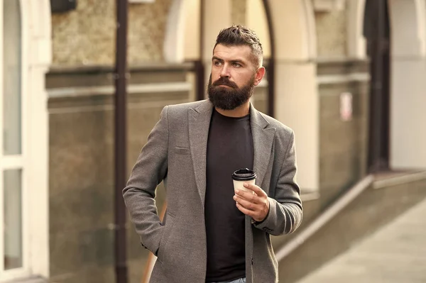 Man bearded hipster drinking coffee paper cup. One more sip of coffee. Drinking coffee on the go. Businessman lumbersexual appearance enjoy coffee break out of business center. Relax and recharge