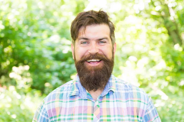 Il a de la magie dans son sourire. Joyeux hipster avec un sourire blanc sain sur le visage non rasé. Barbu avec un grand sourire blanc sur le paysage naturel. Caucasien gars avec des cheveux élégants et sourire heureux le jour de l'été — Photo