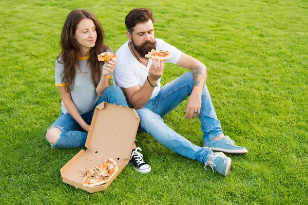 Taste of satisfaction. summer picnic on green grass. happy couple eating pizza. Healthy food. fast food. bearded man hipster and adorable girl eat pizza. hunger. family weekend. couple in love dating — Stock Photo, Image