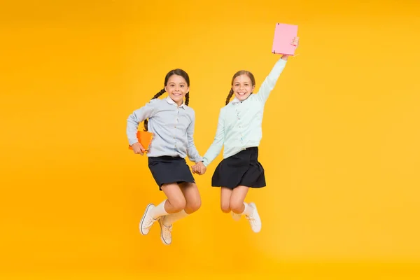 Leidenschaft für Bücher. fröhliche kleine Mädchen springen mit Büchern auf gelbem Hintergrund. Niedliche kleine Kinder lächeln mit Enzyklopädie oder Handbüchern. Lehrbücher für Schüler und Studenten — Stockfoto