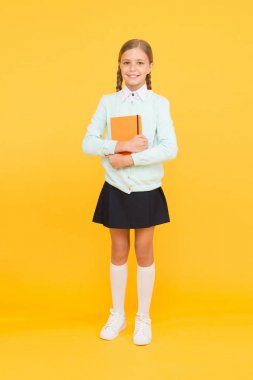 Gelecek için sağlam bir bilgi tabanı. Sarı arka plan üzerine kitap tutan sevimli küçük bir kız. Elinde kitap bilgisi olan sevimli küçük bir çocuk. Bilgi ve beceriler. Bilgi günü veya 1 Eylül