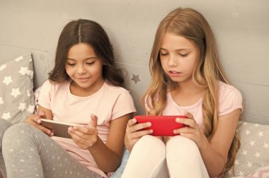 Çocuk eğlencesi başvurusu. İnternet sörfü ve ebeveynlik danışmanlığı yok. Akıllı telefon internet erişimi. Kız kardeşler akıllı telefonlarla meşgul pijama giyerler. Pijamalı çocuklar akıllı telefonlarla etkileşim halindedirler.