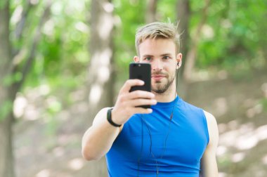 Uygulamayı kullanarak rota çalıştır'ı oluşturun. Akıllı telefon ve akıllı saatli sporcu koşuya hazırlanın. Spor uygulaması ile eğitim daha eğlencelidir. Adam akıllı telefon koşuya başlamaya hazır. Uygulamayı ayarlama