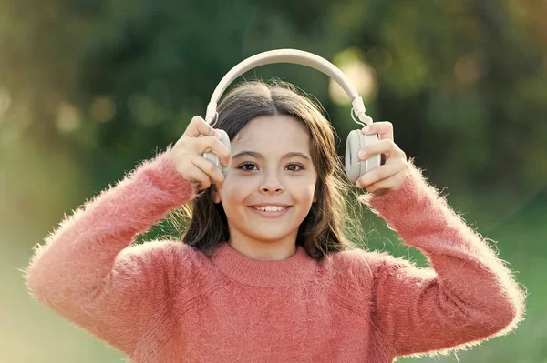 All she wants to hear is music. Adorable little girl outdoor. Little girl child wearing headphones. Happy child enjoy listening to music on the go. Having incredible sound for all her entertainment