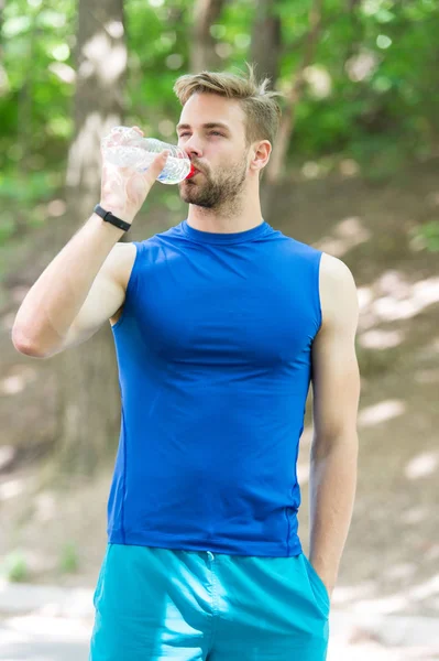 Forfriskende drikke. En atletisk idrettsmann holder flaskevann. Mannlige sportsklær bryr seg om vannbalanse. Sunn livsstil. Drikkevann fra idrettsutøvere etter trening i park. Vitaminer og mineraler – stockfoto