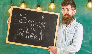 Eğitim ve eğitim kavramı. Sakal ve bıyık yüz memnuniyetle öğrencilerin yüz buruşturma, kara tahta arka plan ile olan adam. Gözlük öğretmen okul için başlıklı yazı tahtası tutar