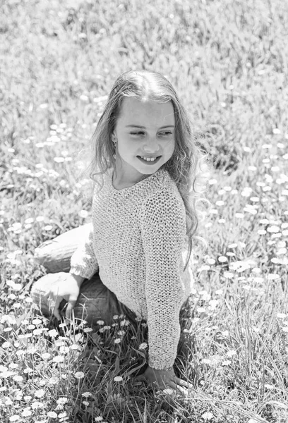 Lány ül a fűben a grassplot, zöld háttér. A Heyday fogalma. A lány mosolygó arca szabadidejüket a szabadban töltik. Gyermek élvezni tavaszi napsütéses Időjárás ülve Meado — Stock Fotó