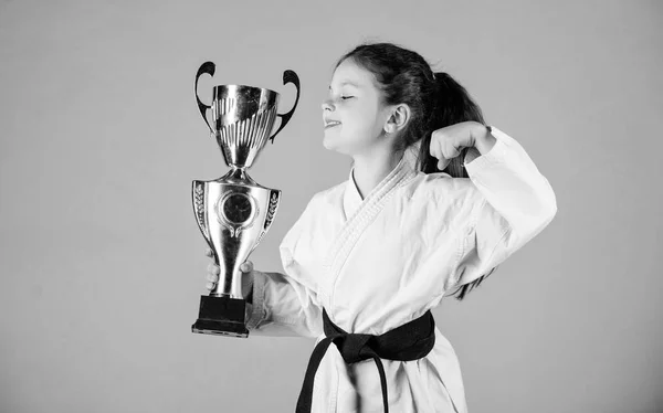 Celebrate achievement. Strong and confident kid. Girl little child in white kimono with belt. Karate fighter child. Karate sport concept. Self defence skills. Karate gives feeling of confidence — Stock Photo, Image