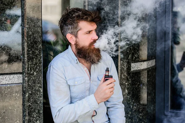 Concepto de hábitos. hombre fumando cigarrillo electrónico. hipster hombre mantenga el dispositivo de vapeo. Hipster maduro con barba. Seguridad y adicción a la salud. inhalando vapor. Barbudo brutal macho fumar cigarrillo electrónico —  Fotos de Stock