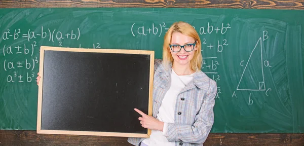 教师显示学校信息。老师聪明微笑的女人拿着黑板空白的广告复制空间。请记住此信息。学校时间表和信息。家乡要求信息 — 图库照片