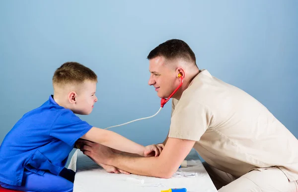 Uomo medico sedersi strumenti medici tavolo esaminando paziente bambino. Assistenza sanitaria. Concetto pediatrico. Il pediatra attento controlla la salute di bambino. Visita medica. Operaio ospedaliero. Servizio medico — Foto Stock