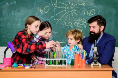 Küçük çocuklar okulda kimya öğreniyor. Okullu bilim adamları bilim okuyor. Mutlu çocuk öğretmenim. Okula dönüyorum. Öğrenciler laboratuvarda mikroskopla bilimsel deneyler yapıyorlar.
