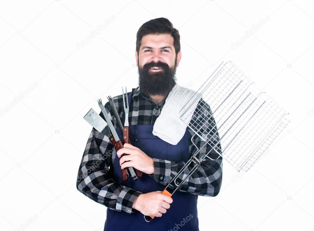 Roasting and grilling food. Man hold cooking utensils barbecue. Tools for roasting meat outdoors. Picnic and barbecue. Tips for cooking meat. Barbecue season. Bearded hipster wear apron for barbecue