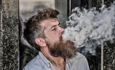 Elektronik sigara içiyor. Stres giderme konsepti. Sigara içme cihazı. Adam uzun sakal sigara alışkanlığı ile rahat. Aromalı duman bulutları. Sakallı adam vape içiyor. Sakallı adam duman solumak