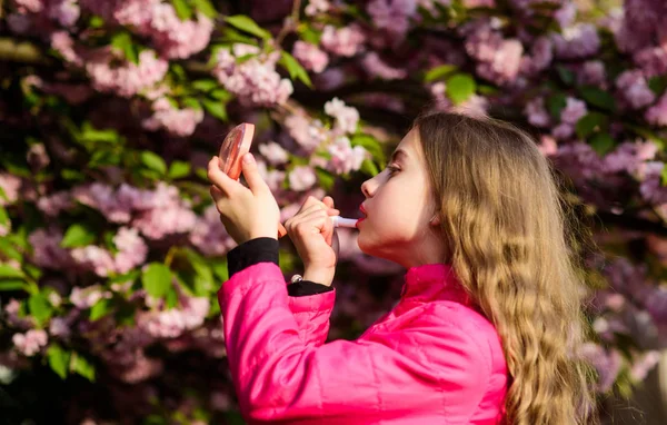 Smell of tender bloom. Sakura flower concept. Gorgeous flower and female beauty. Natural cosmetics for skin. Girl in cherry flower. Kid with lipstick makeup. Small girl child in spring flower bloom