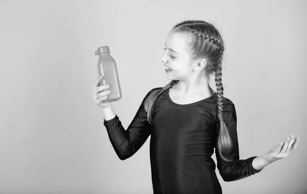 Dziecko czuje pragnienie po treningu sportowym. Dziecko cute girl gimnastyk sportowy trykot trzymać butelkę do picia. Równowaga wodna i trening twardej siłowni. Pij więcej wody. Trzymaj butelkę z wodą. Pragnienie ugasić — Zdjęcie stockowe