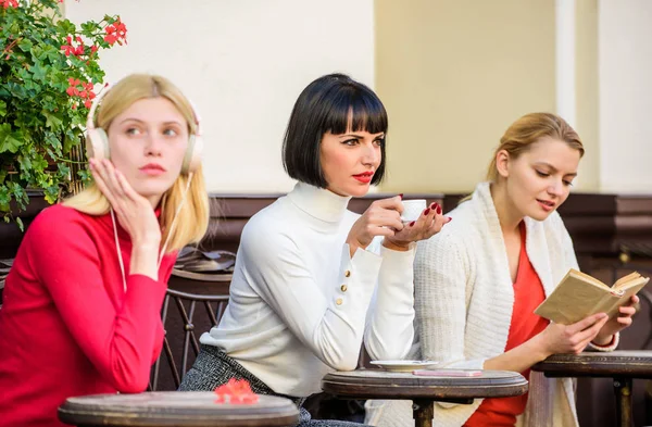 Different interests. Weekend relax and leisure. Coffee cafe. Way to relax and recharge. Female leisure. Group pretty women terrace entertain themselves with reading and listening. Hobby and leisure