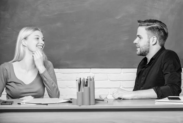 Intelligente e sicuro di sé. Insegnante e maestra seduti alla scrivania. Un bell'uomo e una bella donna tornano a scuola. Studenti universitari o universitari. Istruzione superiore. Coppia che studia in classe — Foto Stock