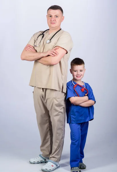 Mały chłopiec z tatą w szpitalu. szczęśliwy dziecko z ojcem z stetoskop. lekarza rodzinnego. medycyny i zdrowia. ojcem i synem w mundurze medycznym. Wszystko musi być idealne. za pomocą stetoskopu — Zdjęcie stockowe