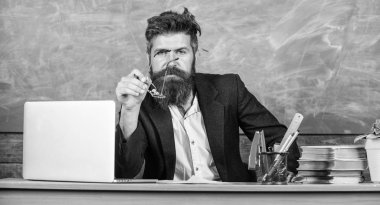 Eğitimci bitmiş bir açıklama sormak şey temiz. Kim soruyu cevaplamak için hazır. Öğretmen hipster gözlük sit sınıf kara tahta arka plan ile sakallı. Okul öğretmeni hazırlamak soru sormak