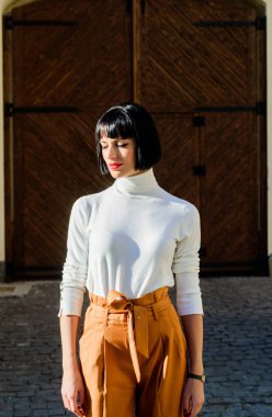 Yüksek belli pantolonlar podyuma dönmeye devam ediyor. Kadın çekici esmer şık kıyafet. Yüksek belli. Kadınlık ve kadınsı rakam vurgulamak. Kız makyaj yüz gevşek yüksek bel pantolon giymek