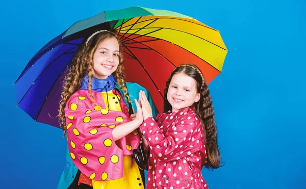 Joyeux enfants hipster, fraternité. liens familiaux. Des petites filles en imperméable. mode d'automne. protection contre la pluie. Arc en ciel. joyeuses petites filles avec parapluie coloré. Sensation de froid — Photo