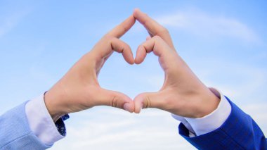 El kalp hareketi parmakları kullanarak şekil oluşturur. Eller kalp şeklinde mavi gökyüzü arka plan bir araya koydu. Aşk sembolü kavramı. Aşk ve romantizm kalp şeklinde jest sembolü erkek eller