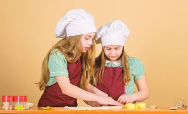 Her şeyi kendi fırınlarımızdan taze pişiriyoruz. Sevimli bayan aşçılar. Aşçı şapkası ve önlük giyen küçük kızlar. Küçük aşçılar kurabiye pişirmek için hamur haddeleme