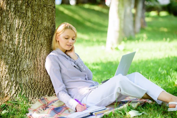 Természeti környezet iroda. Munka a szabadban ellátások. Nő a laptop számítógép munka szabadban sovány a fa törzs. Lány dolgozik laptop parkban ülni füvet. Oktatási technológia és Internet-koncepció — Stock Fotó