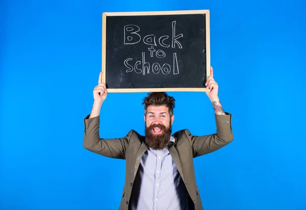 Tanár szakállas férfi birtokolja tábla felirattal vissza az iskolába kék háttér. Tanítás stresszes foglalkozás. Ne légy ideges. Tanár kócos haja stresszes a tanév elején — Stock Fotó