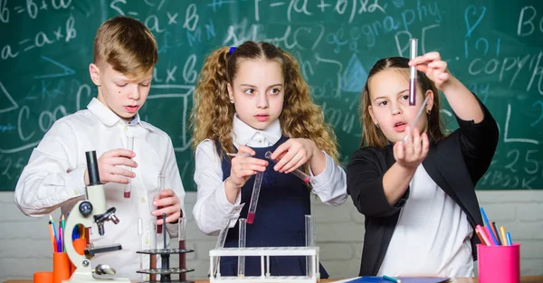 School laboratory. Group school pupils study chemical liquids. School chemistry lesson. Test tubes with substances. Formal education. Girls and boy student conduct school experiment with liquids