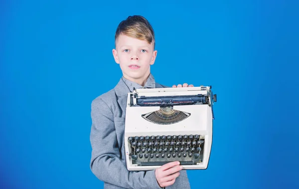 Boy hold retro typewriter on blue background. What to do with this thing. Out of date. I need modern gadget instead this retro. Outdated gadget. Retro and vintage. Yard sale. Retrospective study